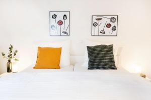 a white bed with an orange pillow and pictures on the wall at Haus Stressfrei - Nordhorn in Nordhorn
