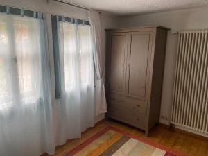 a room with two windows and a cabinet with curtains at Schöne Tage im Denkmal in Bittstädt