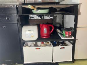 a kitchen shelf with a red appliance on it at 民泊寿屋Kotobukiya Guesthouse in Muroran