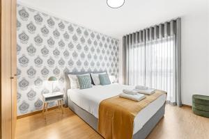 a bedroom with a large white bed and a window at GuestReady - Gaia Gardens Apartments in Vila Nova de Gaia +184 photos