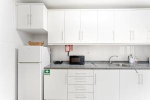 a white kitchen with a sink and a microwave at GuestReady - Gaia Gardens Apartments in Vila Nova de Gaia