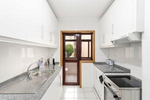a white kitchen with a sink and a door at GuestReady - Gaia Gardens Apartments in Vila Nova de Gaia