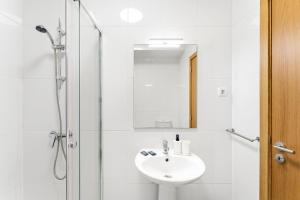a white bathroom with a sink and a shower at GuestReady - Gaia Gardens Apartments in Vila Nova de Gaia