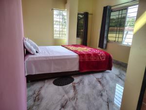 a bedroom with a bed with a red blanket on it at Shivmandir Homestay in Siliguri