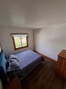 a small bedroom with a bed and a window at Habitación privada en Coñaripe de 1 Cama in Coñaripe