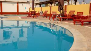 a swimming pool with red chairs and tables and chairs at Don Checho's House in Ica