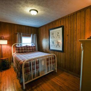 a bedroom with a bed in a room with wooden walls at Settler - by The Chalets in Logan