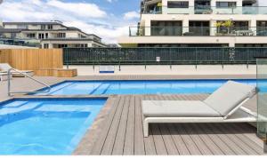 a swimming pool with a lounge chair next to a building at Oceanside Paradise 344 in Mount Maunganui