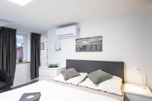 a white bedroom with a bed and a chair at Kolonie Apartments in Žabovřesky