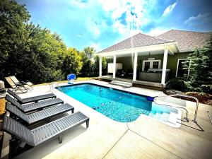 a swimming pool with chairs and a house at Bourbon Trail Pool & Hot-Tub FUN-ZONE! Game Room! Pool Table! Golden Tee! Ping Pong! Luxurious and Spacious Master Bedroom! Fishing Offsite! in Springfield