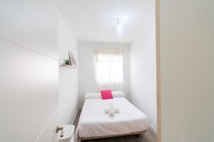 a small white room with a bed with a pink pillow at Avenida Principal muy cerca de la playa - By Aloha Palma in Águilas