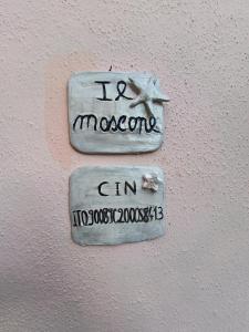 two signs on the side of a white wall at Il Mascone in Stintino +21 photos