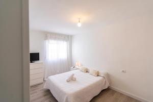 a white bedroom with a bed and a television at Avenida Principal muy cerca de la playa - By Aloha Palma in Águilas