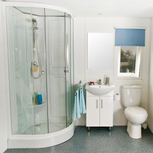 a bathroom with a shower and a toilet and a sink at Parque de Campismo Orbitur Sagres in Sagres