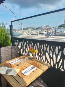 a wooden table on a balcony with a view of a harbor at Logis HOTEL RESTAURANT La Régence in Cherbourg en Cotentin