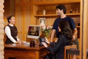 a man and two women standing around a table with a laptop at Casa Santa Clara - Colonial Boutique Hotel in Quito