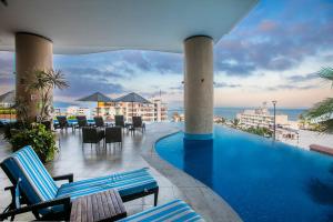 a swimming pool with chairs and a view of the ocean at Pinnacle Resorts 180 in Puerto Vallarta