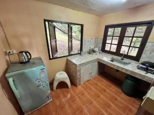 a kitchen with a sink and a refrigerator and two windows at Chaloklum Belvedere B6 in Ko Phangan