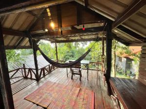 a hammock on a wooden deck with a table and chairs at Chaloklum Belvedere B6 in Ko Phangan
