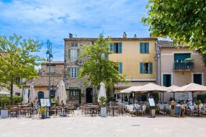 an outdoor cafe with tables and umbrellas in front of a building at Le Grimaldi in Cagnes-sur-Mer