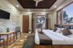 a bedroom with a bed and a desk and a tv at Hotel Elegant Dreamscape Kasauli by Splendid Retreat Hotels in Kasauli
