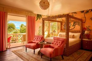 ein Schlafzimmer mit Himmelbett und zwei Stühlen in der Unterkunft Coral Sands Inn & Cottages in Harbour Island + 134 Fotos