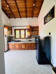 a kitchen with wooden cabinets and a black refrigerator at Sunil VIlla in Talpe