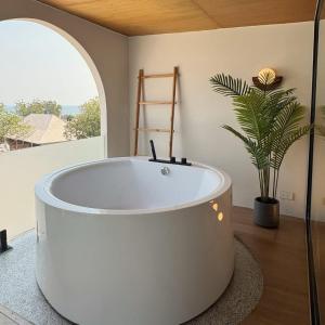 a white bath tub in a room with a plant at Wanderlust HAUS in Ko Larn