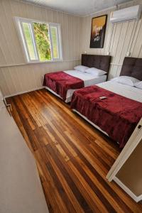 two beds in a room with wood flooring at ROTA DA SERRA casa completa com ar-cond in Orleans
