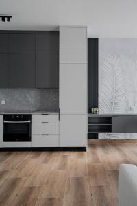 a kitchen with black and white appliances and wooden floors at Apartamenty Szelągowskiej in Raszyn