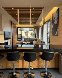 a kitchen and living room with a bar with chairs at La Villa Kfardebian Stone Villa in Fārayyā