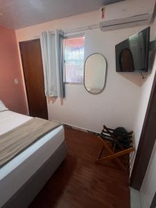 a bedroom with a bed and a mirror and a tv at Casa Brisa Noronha in Fernando de Noronha