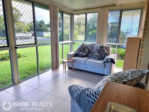 a screened in porch with a couch and chairs at Eden Cottage in Woorim