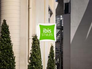 a sign on the side of a building with trees at ibis Styles Brugge Centrum in Bruges