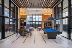 a pool table in the middle of a room with windows at All Batel - Suyts in Curitiba