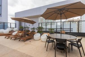 a patio with a table and chairs and umbrellas at All Batel - Suyts in Curitiba +16 photos