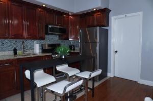 a kitchen with wooden cabinets and a black table with white chairs at New York private room 31 in West New York