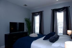 a bedroom with a bed with blue sheets and windows at New York private room 31 in West New York