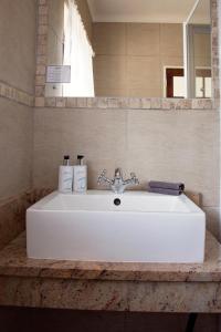 La salle de bains est pourvue d'un lavabo blanc et d'un miroir. dans l'établissement Bayside Guesthouse, à Port Elizabeth