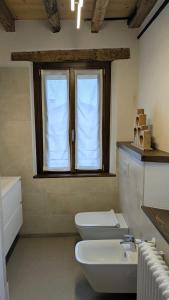 a bathroom with a toilet and a sink and a window at Locanda alla Nave in Pianzano