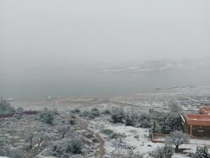 a snow covered field with a house and a lake at Tigmi Nlkhir in Aït Irizane