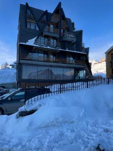 a house in the snow with a car in front at Nirvana Stays Gudauri in Gudauri