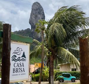 a sign with a palm tree in front of a mountain at Casa Brisa Noronha in Fernando de Noronha