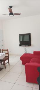 a living room with a red couch and a tv on a wall at Hospedagem mobiliada in Tupã