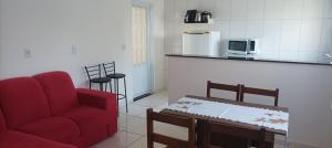 a living room with a red couch and a table at Hospedagem mobiliada in Tupã