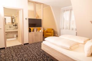 a hotel room with two beds and a television at Hotel Kloster Nimbschen 4 Sterne in Grimma +34 photos