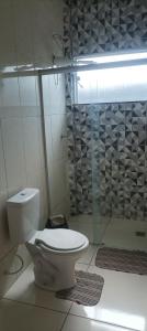 a bathroom with a toilet and a glass shower at Hospedagem mobiliada in Tupã