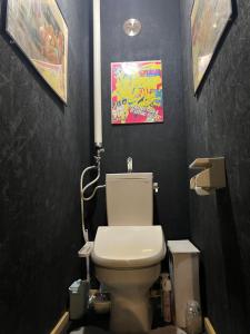 a bathroom with a toilet and a painting on the wall at 民泊寿屋Kotobukiya Guesthouse in Muroran