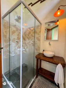 a bathroom with a glass shower and a sink at Chalés Canoa in Ilhabela +10 photos