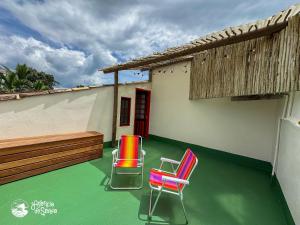 two chairs sitting on a green floor next to a building at Chalés Canoa in Ilhabela